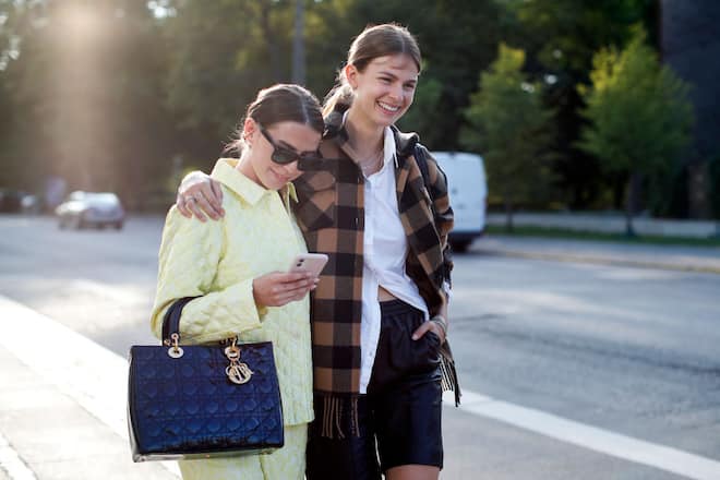 COPENHAGEN, DENMARK - AUGUST 11: Influencer Sarah Lou Falk, wearing a yellow suit by Mads Norgaard, a black bag by Dior and sunglasses by Ray Ban with influencer Jacqueline Zelwis, wearing a yellow black checked jacket with fringes by Sandro, a white blouse by Gestuz, black a black shorts by Meotine and chains by Black Palms the Label during a street style shooting at Copenhagen Fashion Week Spring/Summer 2021 on August 11, 2020 in Copenhagen, Denmark. (Photo by Streetstyleshooters/Getty Images)