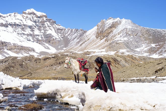 woman playing on a snowy riverside in mountain landscape