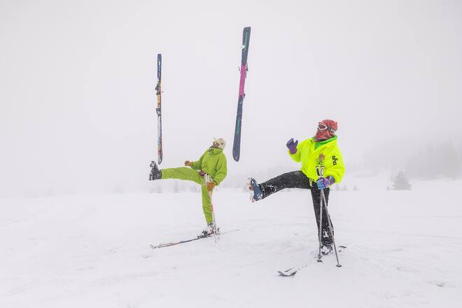 two skiers lifting one ski with one leg