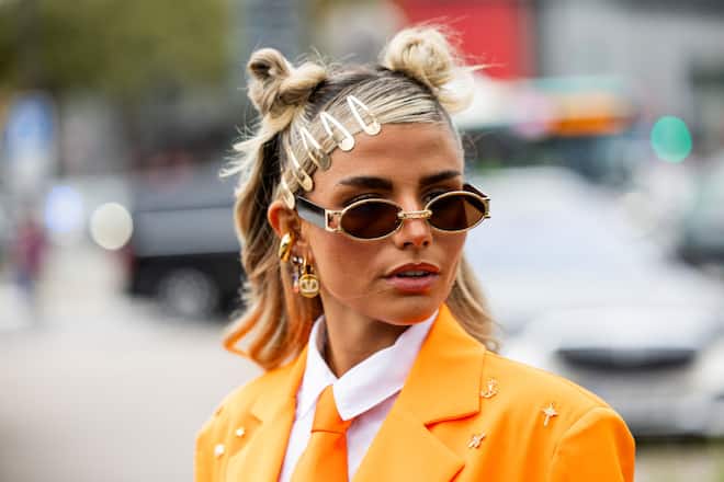 PARIS, FRANCE - SEPTEMBER 29: A guest wears orange tie, white button shirt, jacket with feathers, sunglasses, hair clips outside Valentino during Womenswear Spring/Summer 2025 as part of  Paris Fashion Week on September 29, 2024 in Paris, France. (Photo by Christian Vierig/Getty Images)