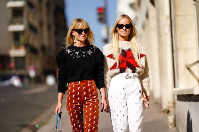 PARIS, FRANCE - SEPTEMBER 27:  A guest (L) wears a black top, red pants ; a guest (R) wears a woll pullover, white flare pants, outside Chloe, during Paris Fashion Week Womenswear Spring/Summer 2019, on September 27, 2018 in Paris, France.  (Photo by Edward Berthelot/Getty Images)