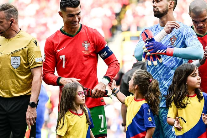 Fussball-EM 2024: Fussball-Superstar Cristiano Ronaldo wird von dem kleinen Einlaufmädchen am Arm berührt.
