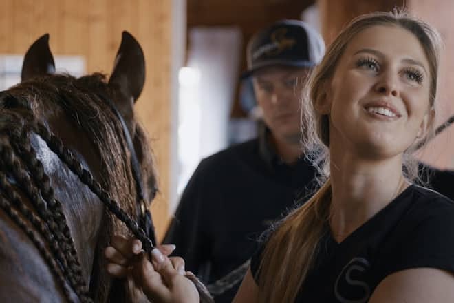 Die Doku «Pferdestärke - Die Welt der Gina Schumacher» begleitet die Tochter von Michael Schumacher in ihrem Alltag, der stark von ihrer Leidenschaft für Pferde und Reiten geprägt ist. Im Hintergrund ist ihr Ehemann Iain Bethke zu sehen.