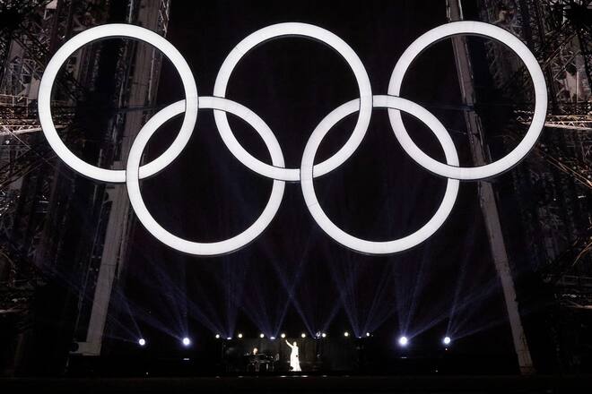 Céline Dion auf dem Eiffelturm unter den olympischen Ringen.