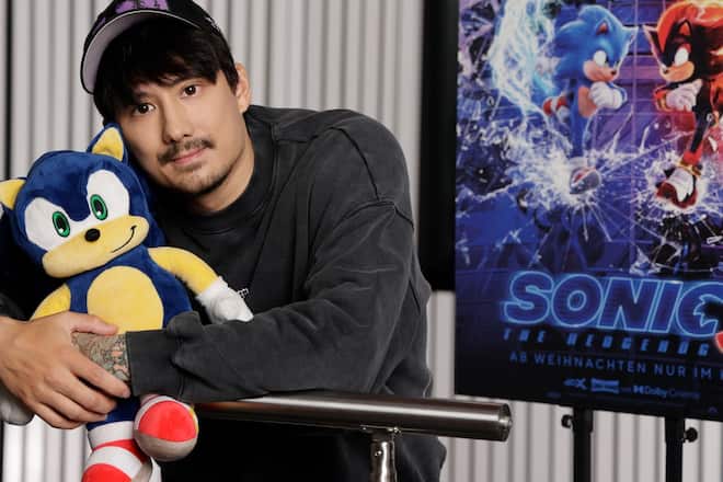 Julien Bam hält den blauen Igel Sonic im Arm, dem er seine prominente Stimme leiht.