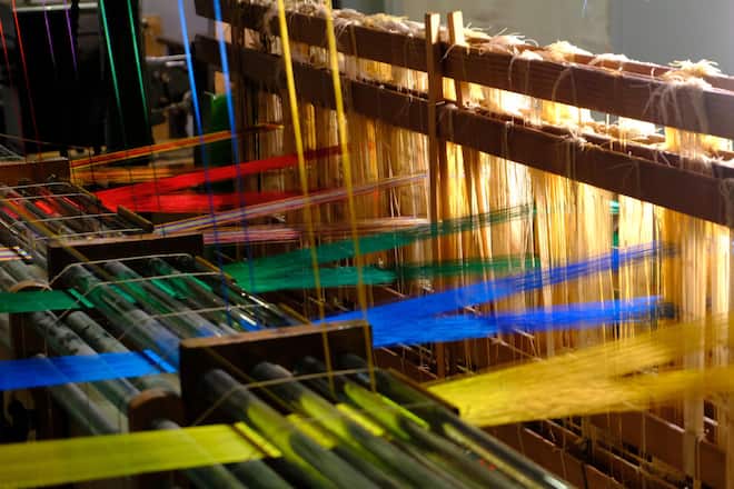 Seidenfäden im Spiel von Licht, Bewegung und Präzision, am historischen Seidenbandwebstuhl.