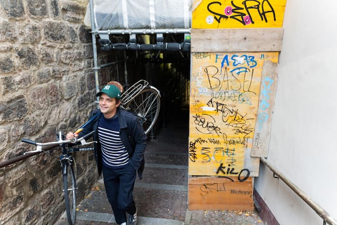 Der Schweizer Schauspieler *Julian Koechlin* ist in Kürze wieder in «Neumatt» und zudem in «Münter & Kandinsky» zu sehen. Wir besuchen ihn in seiner Heimat Basel und gehen durch die Stadt, ehe er zu seinem Bruder geht. Koechlin ist Grosser Bretagne Fan. Seinen Segler Pullover und seine Arbeiter Jake kommen von dort. Sein Fahrrad ist, wie es sich ein Fan des französischen Designs gehört, ein Peugeot. Basel (BS)