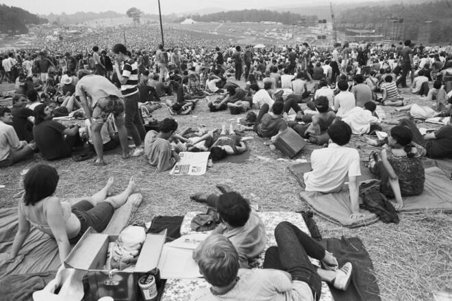 Audience members sit out of view of the stage at the free Woodstock Music and Art Fair. The festival took place on Max Yasgur's dairy farm, which he rented to event organizers for $75,000. About 450,000 people attended the three day concert, which turned into chaos due to the crowds, heavy rains, and traffic jams. It is nonetheless romantically remembered as a symbol of the liberal spirit of the hippie generation. | Location: Near Bethel, New York, USA. (Photo by Henry Diltz/Corbis via Getty Images)