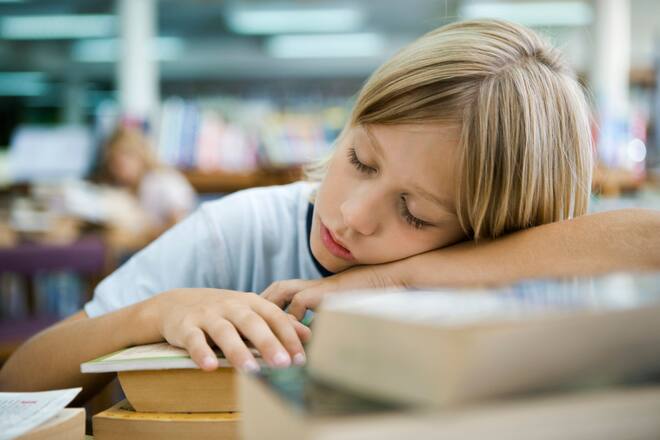 Kind schläft über Bücherberg