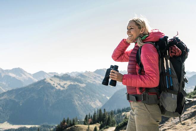 Austria, Tyrol, smiling woman with binoculars on a hiking trip