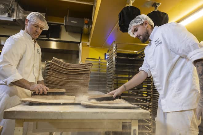 <p>Gekonnt: Frédéric Ressel und Kevin Emberger stauben die fertigen Leckerly-Platten ab, ehe sie zu feinen Rechtecken geschnitten und weiterverarbeitet werden.</p>