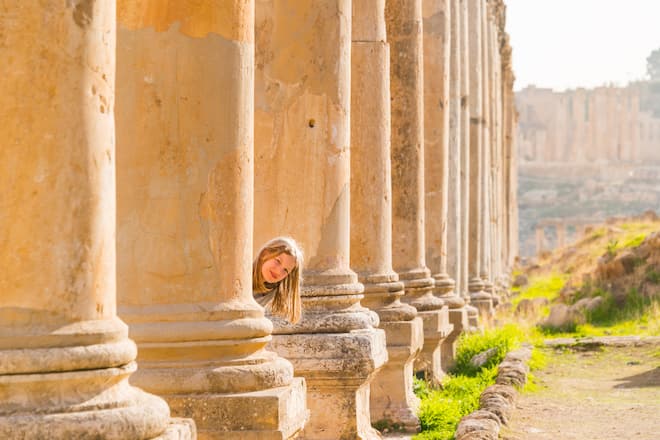 9 years old girl hiding after corinthian columns at Roman city, Jerash, Jordan, Middle East