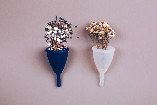 Two menstrual zero waste cups with confetti and chamonile. Alternative reusable product female hygiene. Flat lay style.