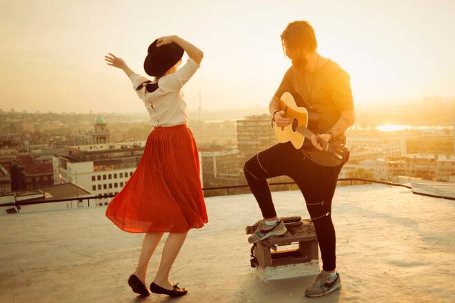 couple dancing on the roof playing the guitar on sunset