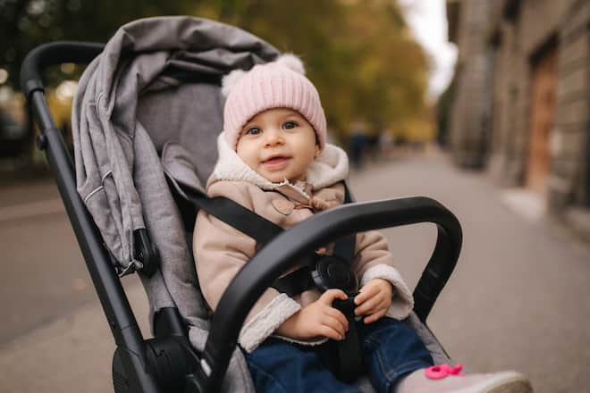 Cute little baby in pram. Adorable baby girl in autumn sitting in her pram.