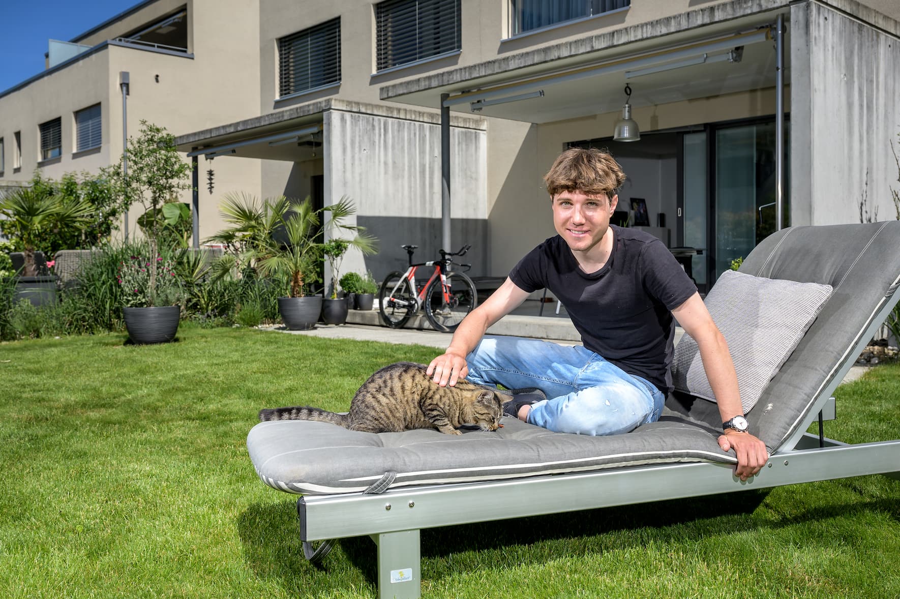 Marc Hirschi, U23-Weltmeister im Radfahren, steht vor seiner ersten Tour de Suisse, ausruhen mit Katze Mira im Garten. Aufgenommen in Ittigen. Bild © Remo Naegeli